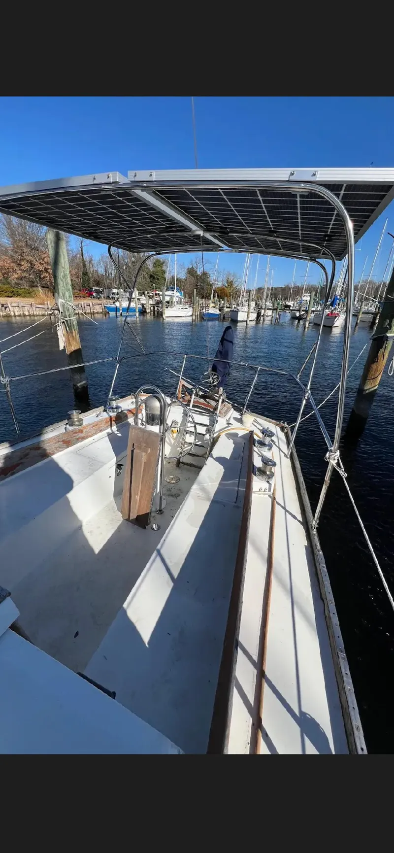Slide: The Image of 1975 Bristol 34 sailboat docked, featuring a spacious deck and canopy under clear blue skies. - 6