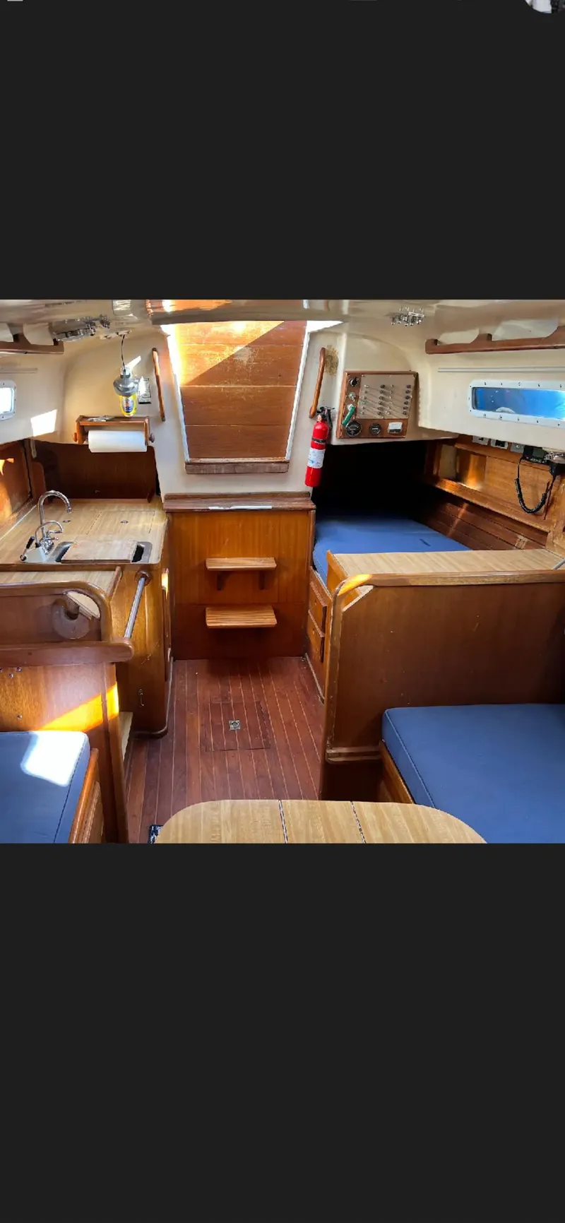 Slide: The Image of Interior of a 1975 Bristol 34 sailboat with wooden furnishings and blue cushions. - 9