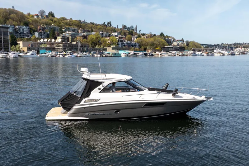Slide: The Image of 2018 Regal 35 Sport Coupe boat on a scenic waterfront with hillside buildings. - 2