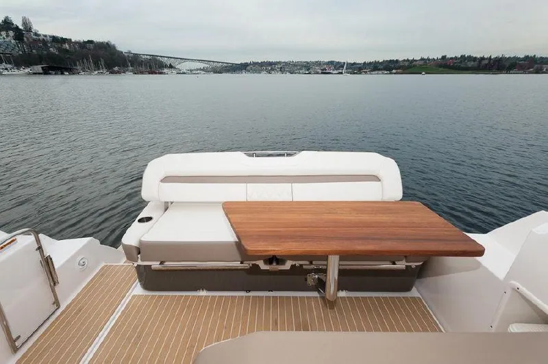 Slide: The Image of 2018 Regal 35 Sport Coupe boat with wooden table and seating, overlooking calm waters. - 35
