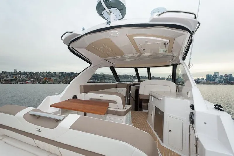 Slide: The Image of 2018 Regal 35 Sport Coupe yacht interior with seating and table, overlooking a scenic waterfront. - 36
