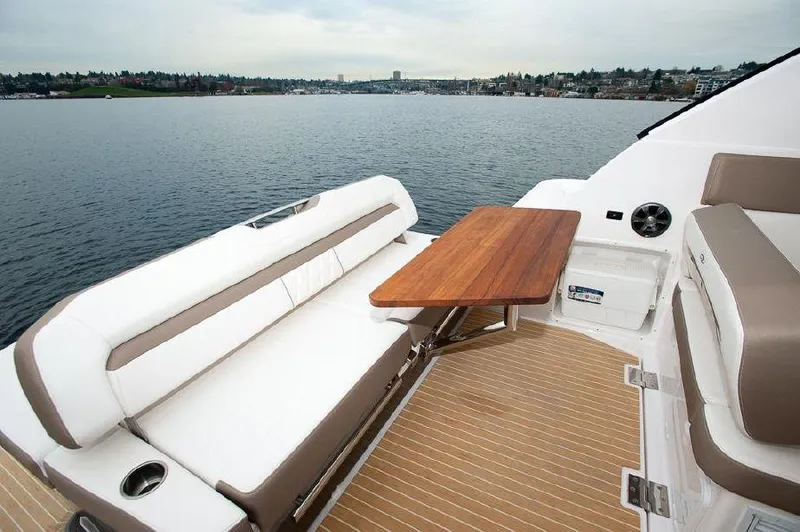 Slide: The Image of 2018 Regal 35 Sport Coupe yacht interior with seating and wooden table on a serene lake. - 39