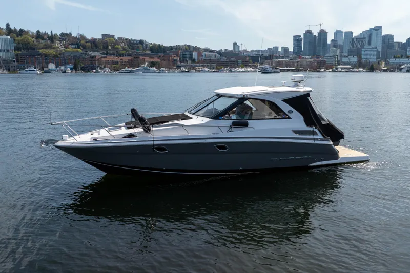 Slide: The Image of 2018 Regal 35 Sport Coupe boat on calm water with city skyline background. - 7