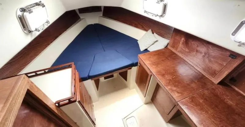 Slide: The Image of Interior of a 1974 Irwin 37 sailboat with wooden cabinetry and blue bedding. - 10