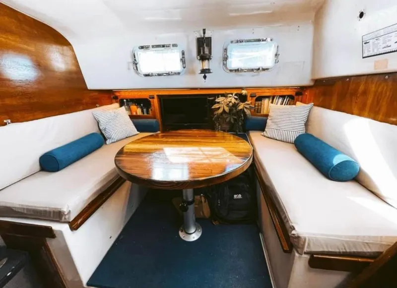 Slide: The Image of 1974 Irwin 37 yacht interior with wooden table, cushioned seating, and nautical decor. - 12