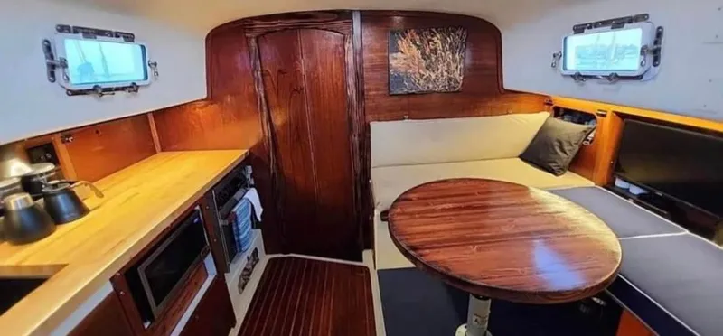 Slide: The Image of 1974 Irwin 37 yacht interior with wooden finishes, cozy seating, and a compact kitchen area. - 13
