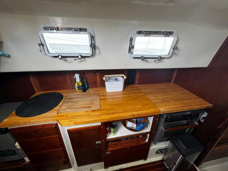 Slide: The Image of 1974 Irwin 37 sailboat galley with wooden countertops and storage cabinets. - 21