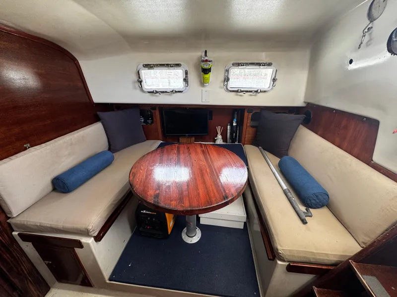Slide: The Image of 1974 Irwin 37 sailboat interior with wooden table, cushioned seating, and porthole windows. - 22