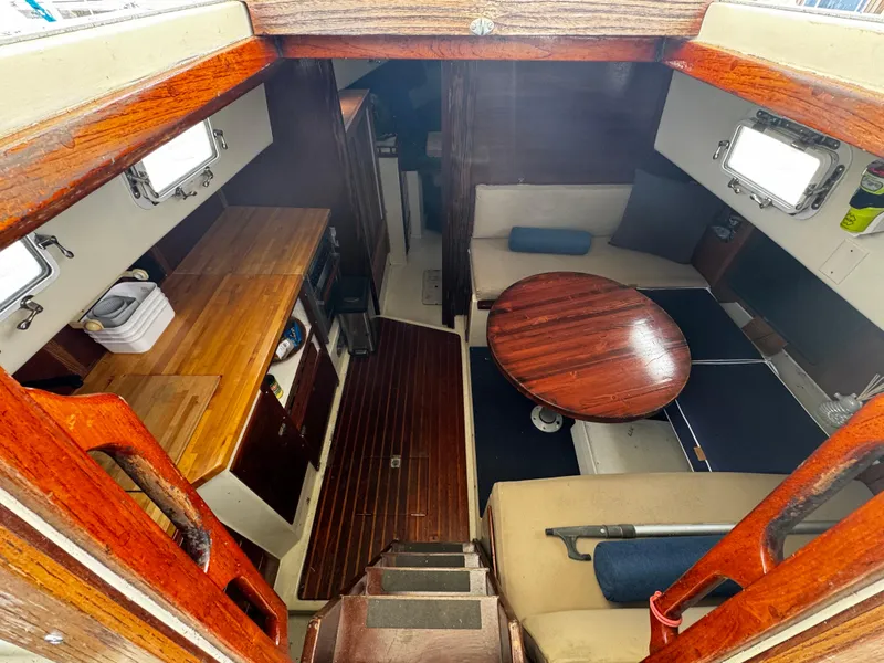 Slide: The Image of 1974 Irwin 37 sailboat interior with wooden table, seating, and compact kitchen area. - 23