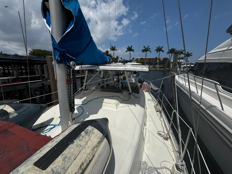 Slide: The Image of 1974 Irwin 37 sailboat docked, featuring blue sail cover and palm trees in the background. - 30