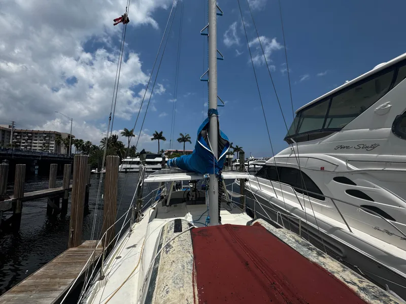 Slide: The Image of 1974 Irwin 37 sailboat docked at marina, clear sky, palm trees in background. - 31
