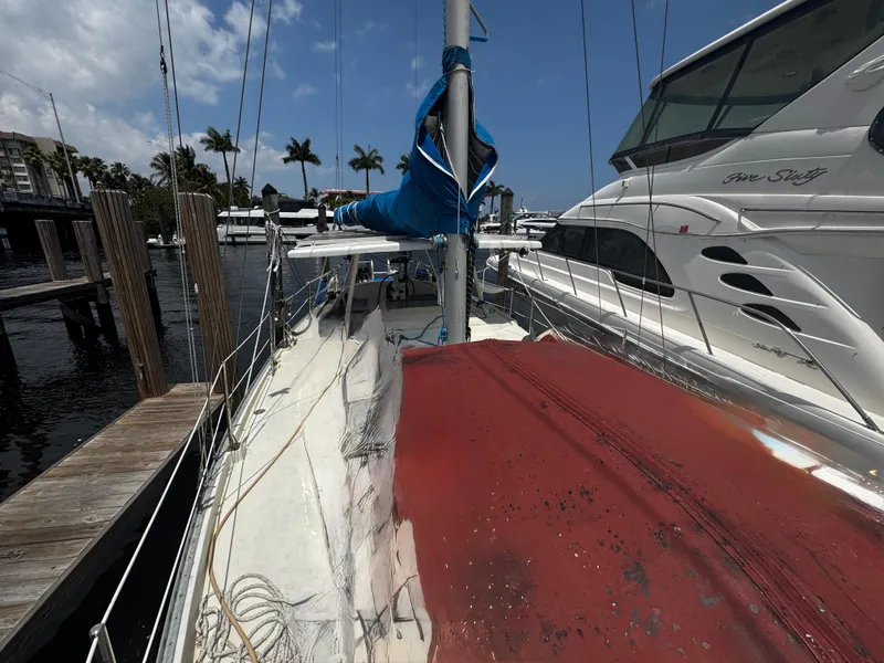 Slide: The Image of 1974 Irwin 37 sailboat docked, with visible deck and mast, surrounded by other boats. - 32