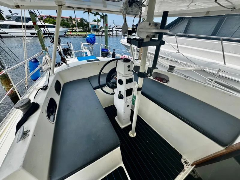 Slide: The Image of 1974 Irwin 37 sailboat cockpit with steering wheel, seating, and marina view. - 34