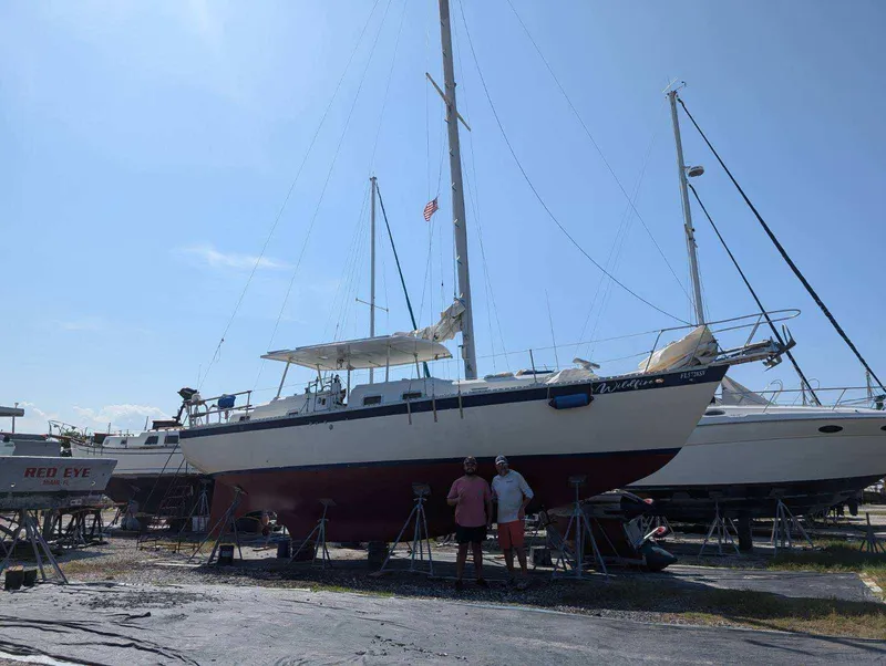Slide: The Image of 1974 Irwin 37 sailboat on land with two people standing nearby. - 41