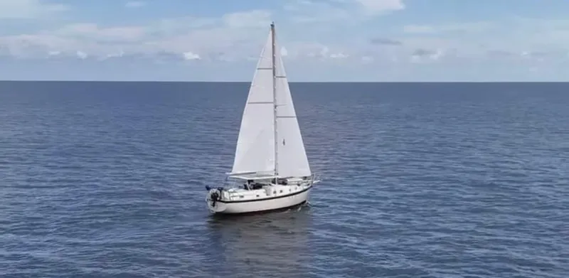 Slide: The Image of 1974 Irwin 37 sailboat on open sea under clear blue sky. - 43