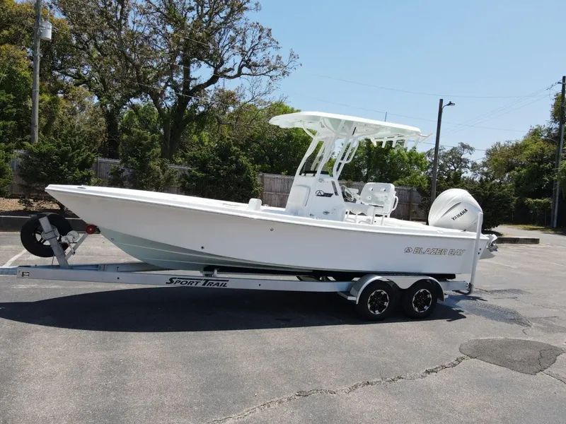 Slide: The Image of 2025 Blazer Bay 2440 boat on trailer in parking lot, side view. - 2