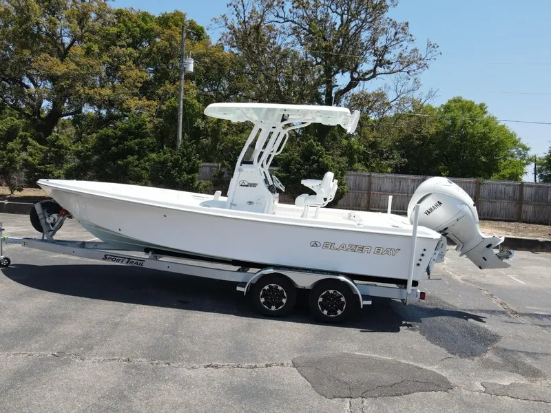 Slide: The Image of 2025 Blazer Bay 2440 boat on trailer, parked outdoors, with trees in the background. - 3