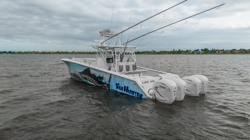 Slide: The Image of 2022 SeaHunter 41 CTS boat on water with triple outboard engines, cloudy sky backdrop. - 3