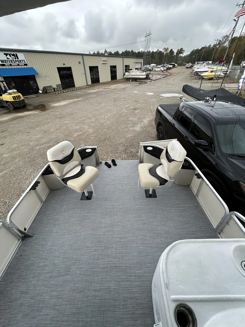 Slide: The Image of 2000 Fisher Freedom 200 DLX pontoon boat with two swivel seats, parked near a dealership. - 10