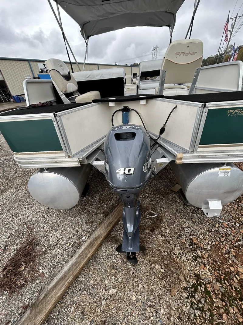 Slide: The Image of 2000 Fisher Freedom 200 DLX pontoon boat with 40 HP outboard motor, parked on gravel. - 4