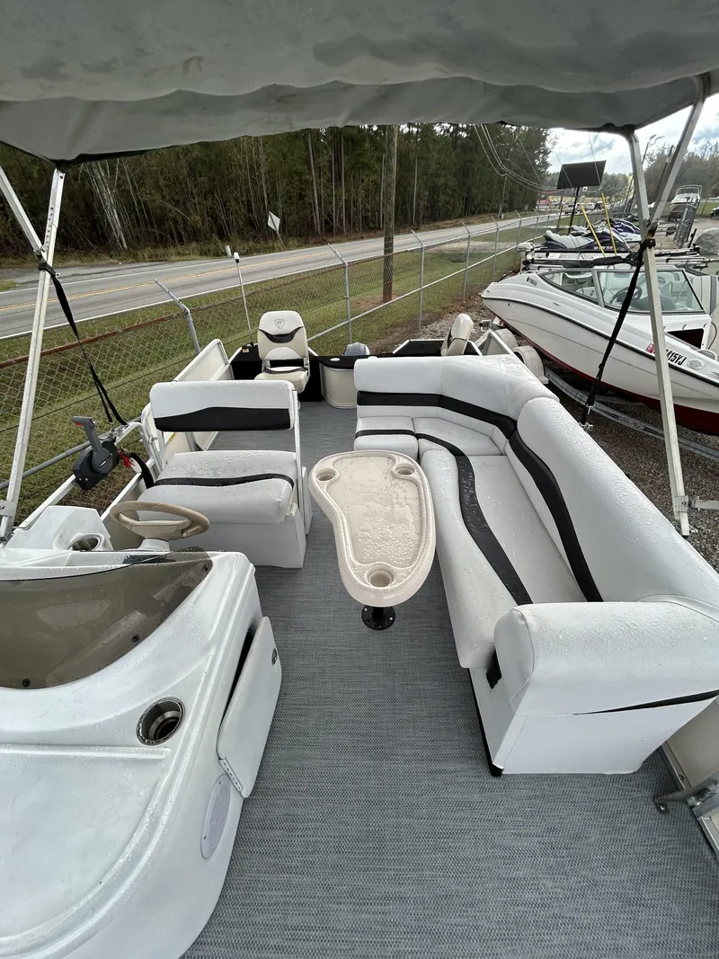 Slide: The Image of 2000 Fisher Freedom 200 DLX pontoon boat with spacious seating and table, parked near a road. - 9