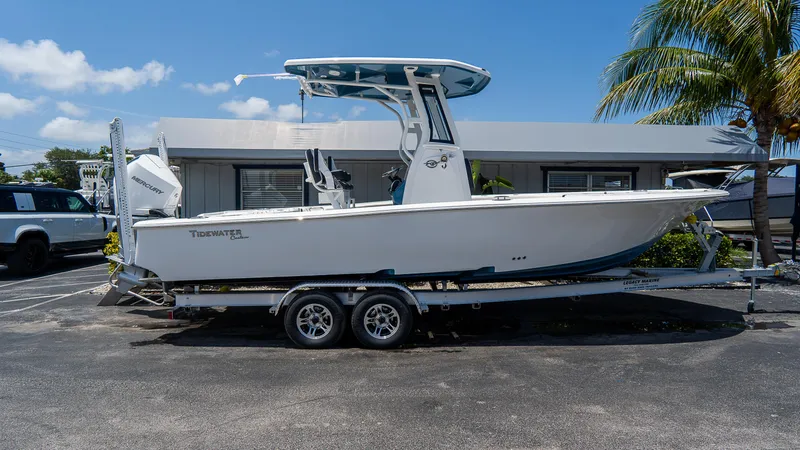 Slide: The Image of 2025 Tidewater 2500 Carolina Bay boat on trailer, parked near palm tree and building. - 30