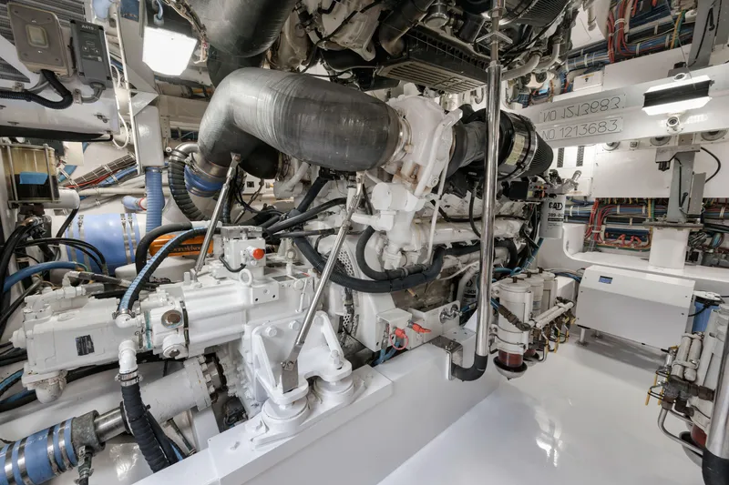 Slide: The Image of Engine room of a 2009 Hatteras 60GT yacht, showcasing complex machinery and piping. - 43