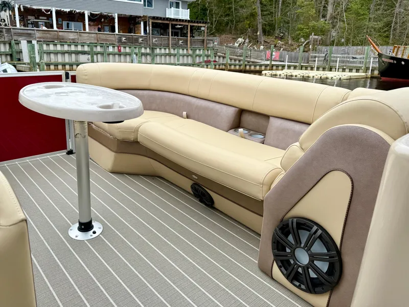 Slide: The Image of 2019 Bentley Pontoons 223 Elite interior with beige seating and table, docked by a wooden fence. - 11