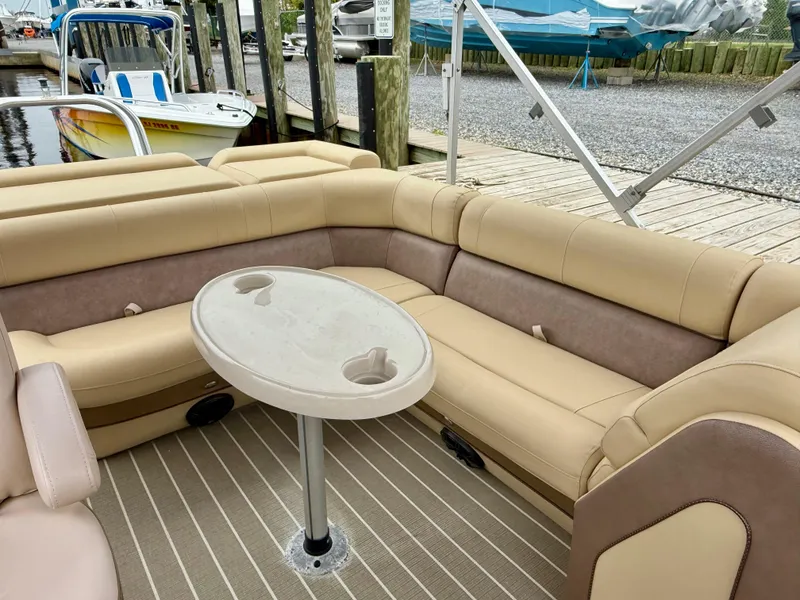 Slide: The Image of 2019 Bentley Pontoons 223 Elite interior with beige seating and table at a dock. - 18