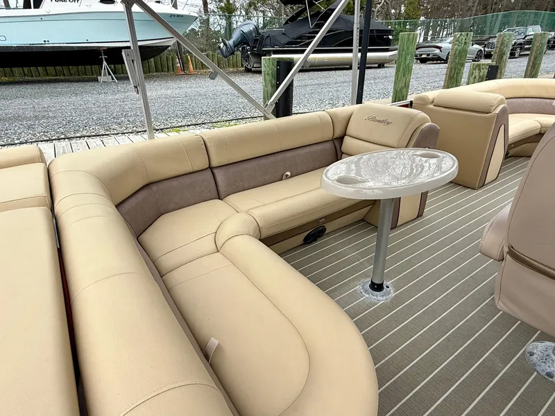 Slide: The Image of 2019 Bentley Pontoons 223 Elite interior with beige seating and a small table. - 19