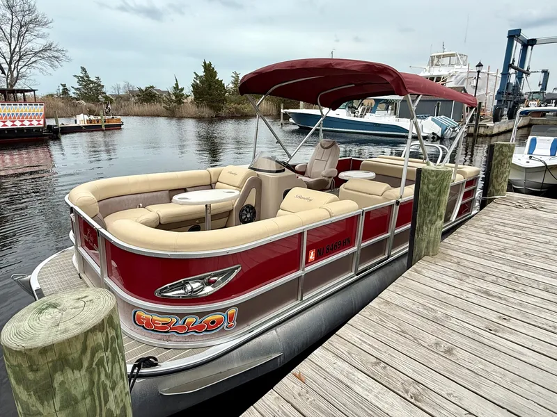 Slide: The Image of 2019 Bentley Pontoons 223 Elite docked, featuring red exterior and beige seating. - 2