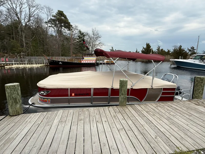 Slide: The Image of 2019 Bentley Pontoons 223 Elite docked by a wooden pier, featuring a red canopy. - 22