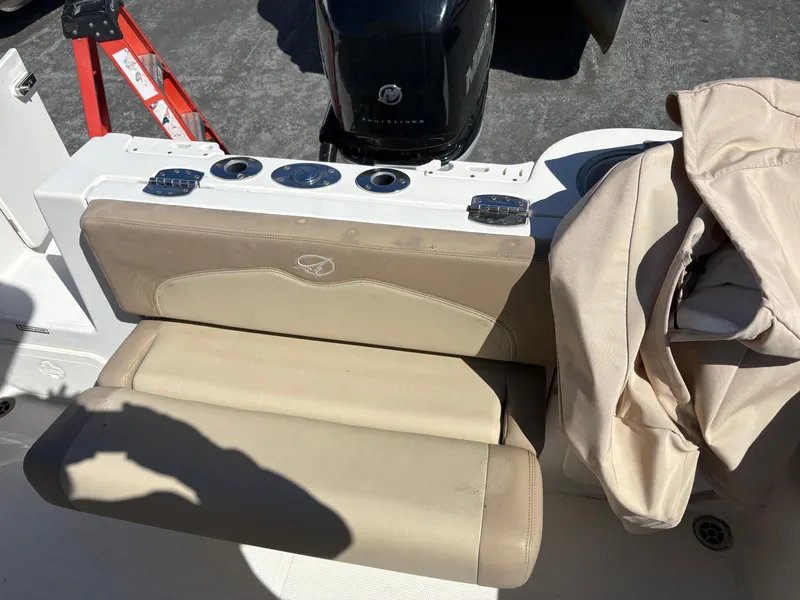 Slide: The Image of 2017 Sailfish 236 CC boat seating area with beige cushions and engine in background. - 18
