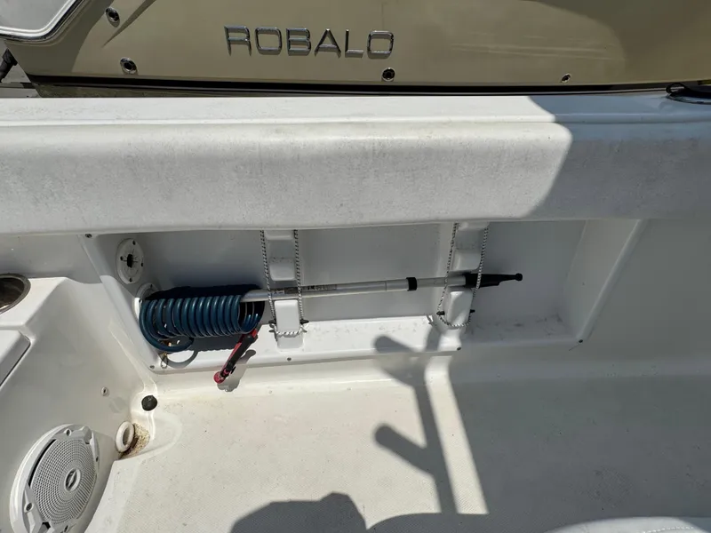 Slide: The Image of 2015 Sea Hunt Ultra 234 boat interior with storage compartment and coiled hose. - 14