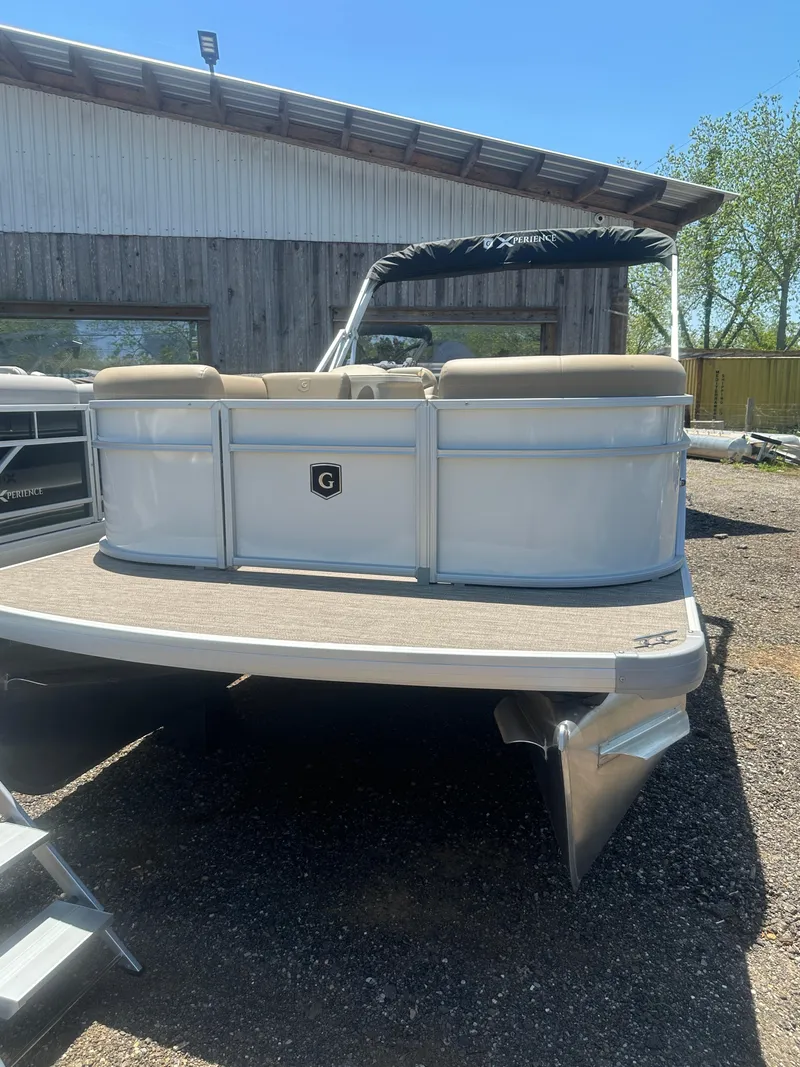 Slide: The Image of 2025 Godfrey Xperience 2086 CXP pontoon boat, parked outdoors near a wooden building. - 2