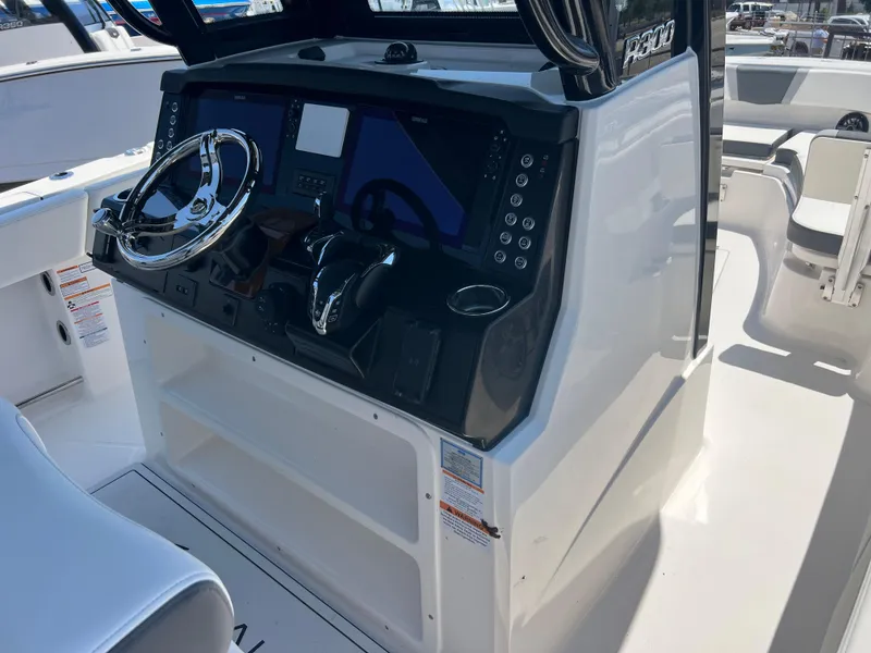 Slide: The Image of 2025 Robalo R300 Center Console boat interior with white seating and cup holders. - 11