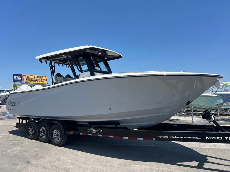 Slide: The Image of 2025 Robalo R300 Center Console boat on a trailer, parked outdoors. - 2