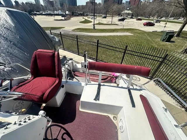 Slide: The Image of 1988 Carver 2767 Santego boat with red seating, parked near a city park. - 18