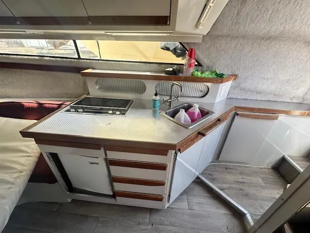 Slide: The Image of 1988 Carver 2767 Santego boat interior kitchen with stove, sink, and storage cabinets. - 21