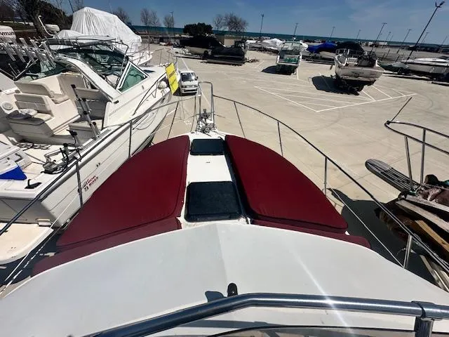 Slide: The Image of 1988 Carver 2767 Santego boat docked, featuring maroon cushions and a spacious deck area. - 17