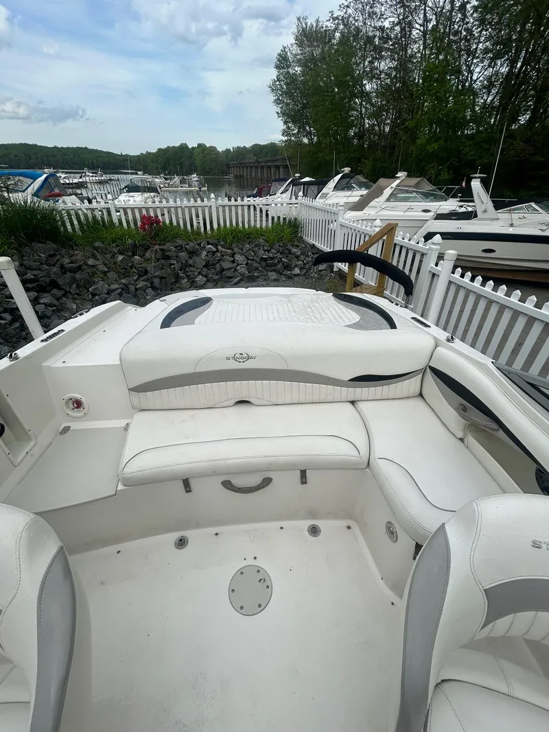 Slide: The Image of 2013 Stingray 208 LR boat interior with white seating, docked near other boats. - 14