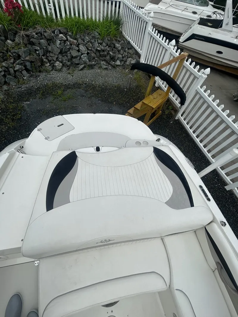 Slide: The Image of 2013 Stingray 208 LR boat with white seating, docked near a white fence. - 15