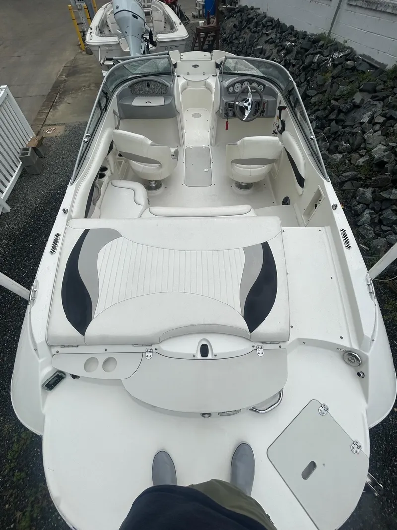 Slide: The Image of 2013 Stingray 208 LR boat with white interior and seating, docked on a rocky shore. - 16