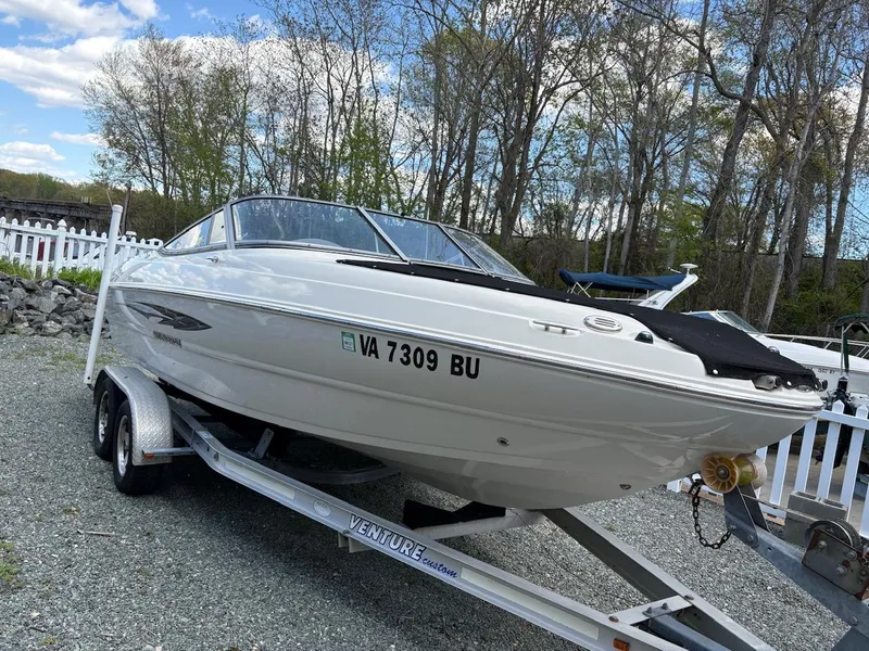 Slide: The Image of 2013 Stingray 208 LR boat on trailer, parked outdoors with trees in background. - 3