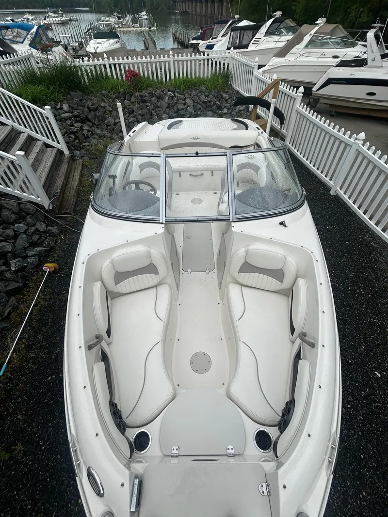 Slide: The Image of 2013 Stingray 208 LR boat docked, surrounded by white fencing and other boats. - 9
