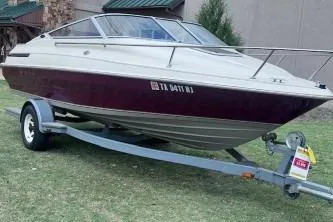 Slide: The Image of 1994 Maxum 2000 SC boat on trailer, parked on grass, with maroon and white exterior. - 7