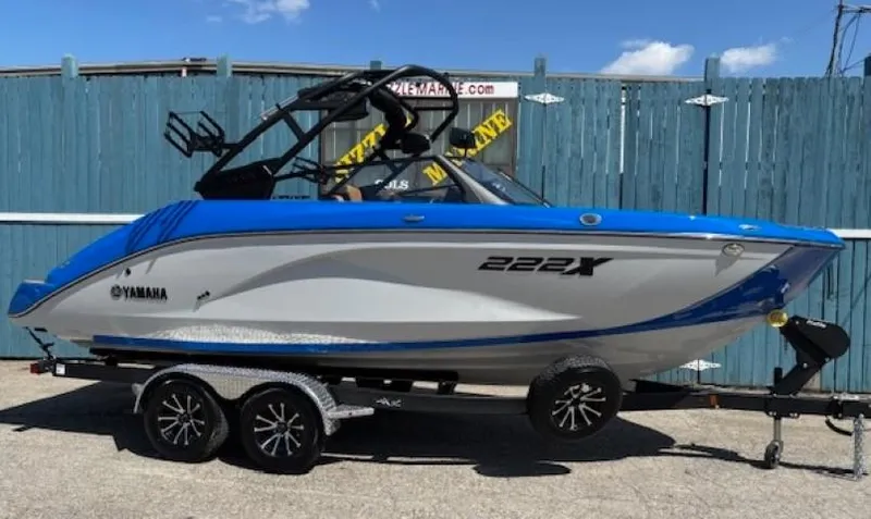 Slide: The Image of 2025 Yamaha Boats 222XD, blue and white, on a trailer, parked outdoors. - 0