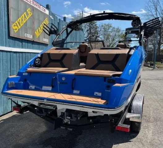 Slide: The Image of 2025 Yamaha Boats 222XD in blue, parked on a trailer at a marina. - 2