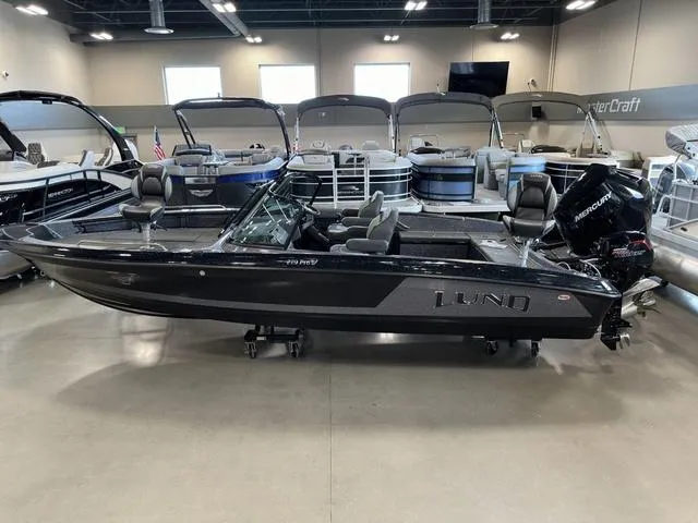 Slide: The Image of 2024 Lund 219 Pro-V GL Sport boat displayed in showroom with other watercraft. - 13