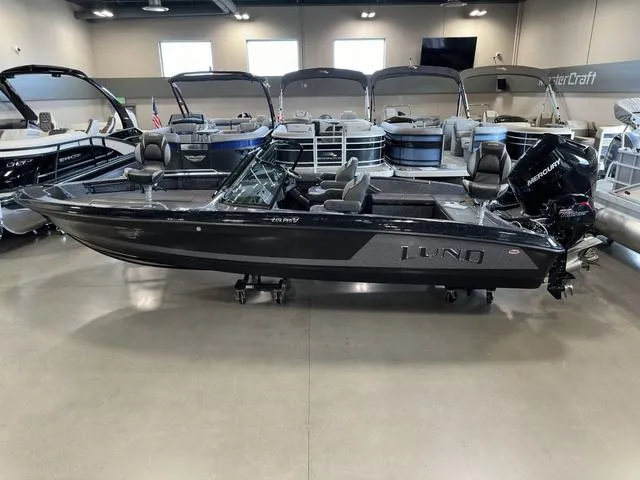 Slide: The Image of 2024 Lund 219 Pro-V GL Sport boat displayed in showroom with sleek design and modern features. - 4
